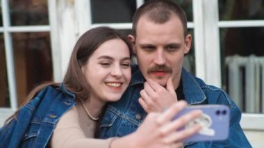 Genç bir çift. Denim giysileri. Eski bir restoranda randevuda, dışarıda. Konuşuyorlar. Oyalanmak. Komik gülüyorlar. Akıllı telefonumla selfie çekiyorum..