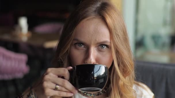 Młoda Kobieta Luźnym Stroju Siedzi Przy Oknie Kawiarni Pije Kawę — Wideo stockowe