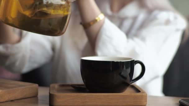 Genç Sarışın Kadını Şeffaf Cam Çaydanlıktan Bir Fincana Çay Dolduruyor — Stok video