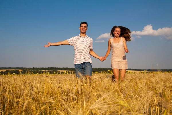 Junges Paar läuft durch Weizenfeld — Stockfoto