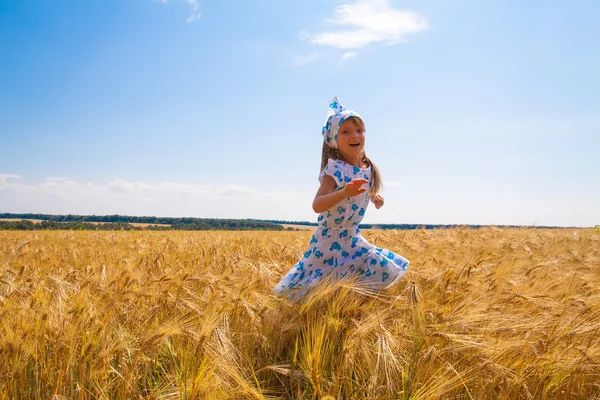 Glückliches kleines Mädchen, das auf einem Feld tanzt — Stockfoto