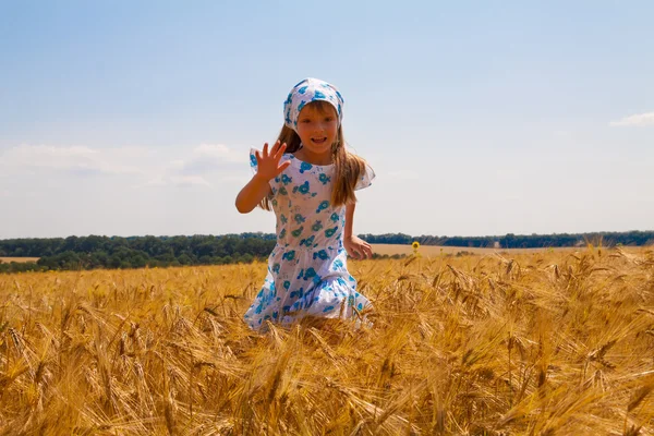 Glückliches kleines Mädchen, das auf einem Feld tanzt — Stockfoto