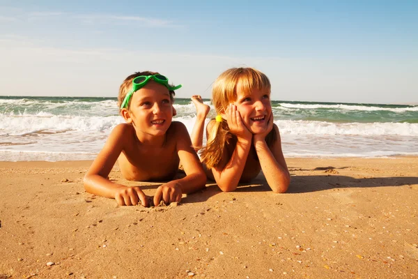 Två glada barn på stranden, havet i bakgrunden. — Stockfoto