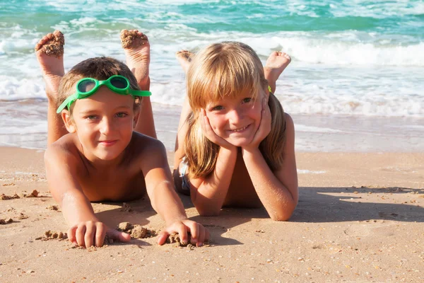 Två glada barn på stranden, havet i bakgrunden. — Stockfoto