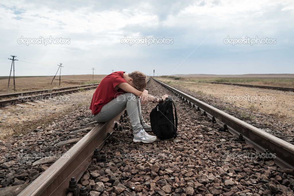 Teen girl with problems sitting on rail road