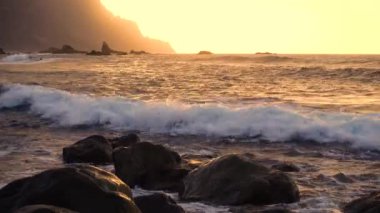 Okyanus dalgaları gün batımında kayalara çarpar Playa Benijo plajı, Tenerife, Kanarya