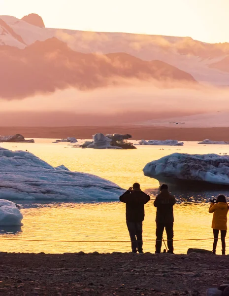 Laguna de hielo. Silueta de turistas tomando fotos de la laguna de hielo puesta del sol. Islandia —  Fotos de Stock