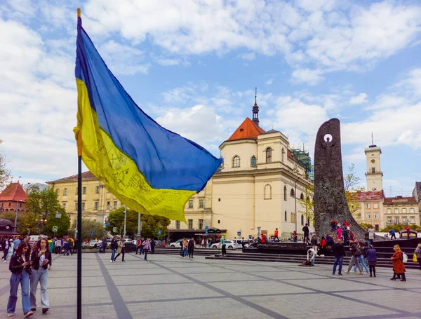 The war in Ukraine. Ukrainian flag against the background of the Lviv City Council and the monument to Taras Shevchenko — Foto de Stock
