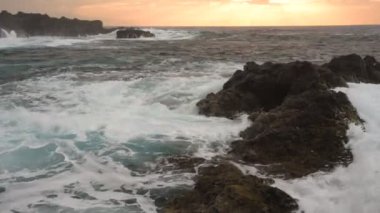 Okyanus dalgaları Tenerife, Kanarya Adaları 'ndaki Playa de Benijo plajı yakınlarında kayalara çarpar ve gün batımını güzelleştirir.