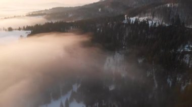 Karpatya dağlarının üzerindeki sis ve bulutlara insansız hava aracı görüntüsü. Güneşli kış, dondurucu soğuk.