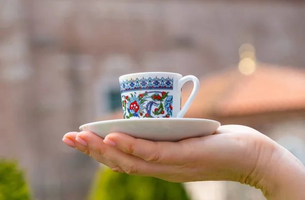 Turkish coffee cup on the palm on the traditional turkish architecture background