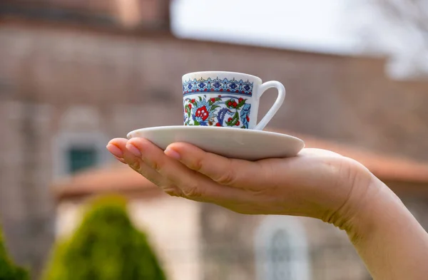 Turkish coffee cup on the palm on the traditional turkish architecture background