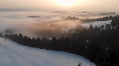Aerial drone view of fog and clouds over Carpathian mountains. Sunny winter frosty day.