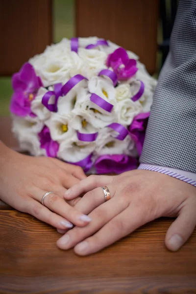 As mãos de um recém-casado no fundo do buquê de casamento — Fotografia de Stock