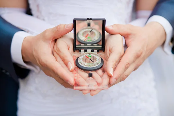 Compass in the hands of the groom and the bride close-up — Stock Photo, Image