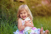 niedliches kleines Mädchen mit einem Hasen hat einen Osterhasen im grünen Gras