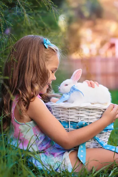 Linda niña con un conejo conejo tiene una Pascua en la hierba verde —  Fotos de Stock