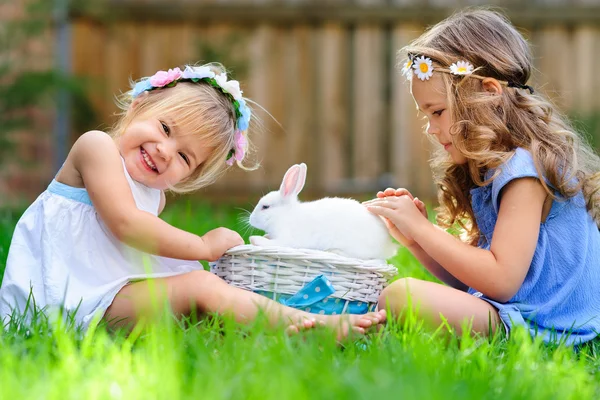 ウサギのウサギを持つ 2 つの小さな女の子は緑の芝生で、イースターを持っています — ストック写真