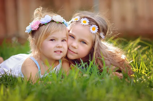 Portrait of two happy little sisters on green grass — Stock Photo, Image