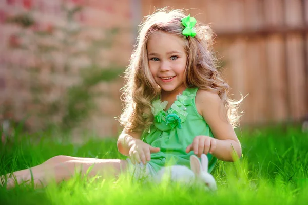 Χαριτωμένο μικρό κορίτσι με ένα κουνέλι έχει ένα Πάσχα στο πράσινο γρασίδι — Φωτογραφία Αρχείου