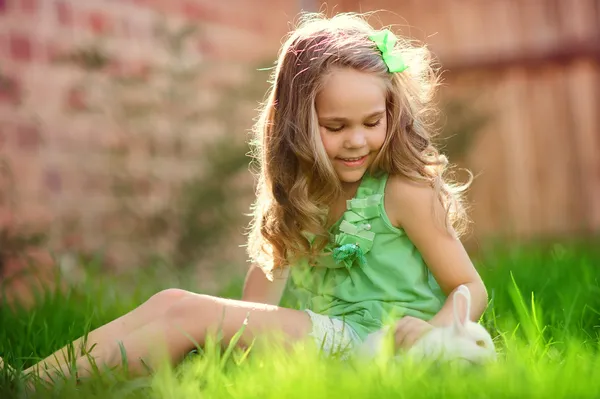 Menina bonito com um coelho coelho tem uma Páscoa na grama verde — Fotografia de Stock