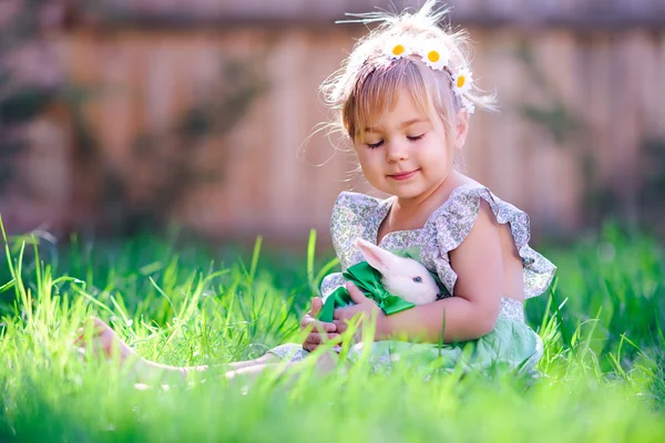 Schattig klein meisje met een konijn heeft een Pasen op groen gras — Stockfoto