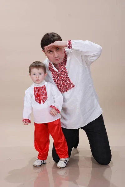 A little boy with his dad, dad looks into the distance. Ukrainian family in vyshyvanka, son and father get to know the world. Father and son Ukrainian style