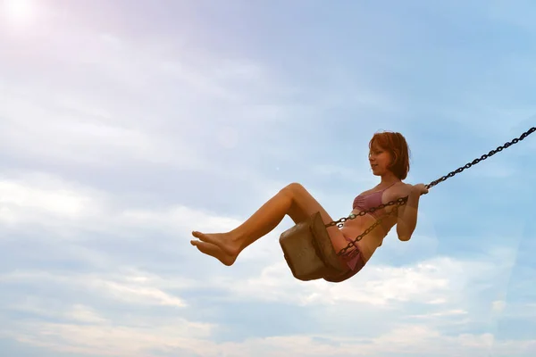 日当たりの良い空に向かってスイングに揺れる水着の少女トーン写真 — ストック写真