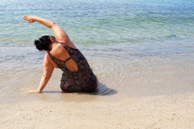Ayyaş kadın deniz kenarında yoga yapıyor, açık havada egzersiz yapıyor..