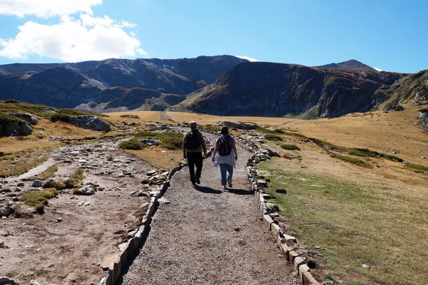 バックパックを持った男と女が山の中の道を歩いている — ストック写真