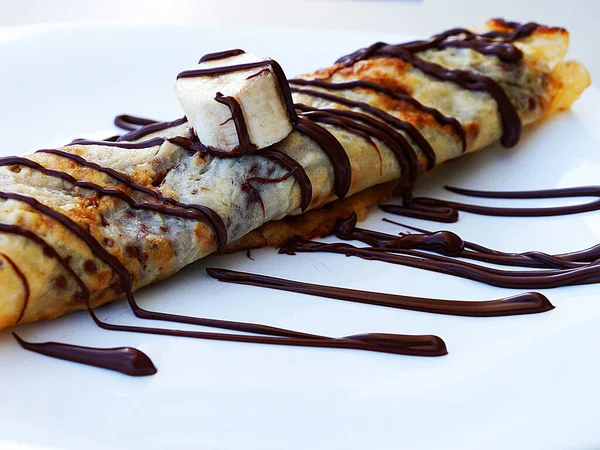 pancake roll with banana and chocolate close-up.