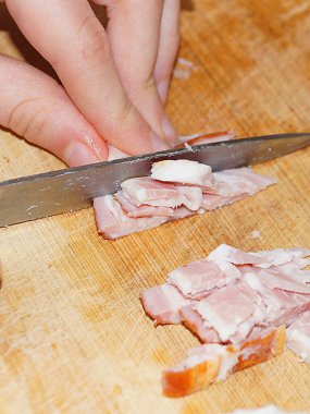 Kadın domuz yağını yakın plan kesim tahtasında bıçakla kesiyor.