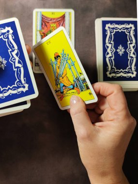 Bir falcı elinde kılıç kartıyla tarot kartlarından bir düzen yapar..