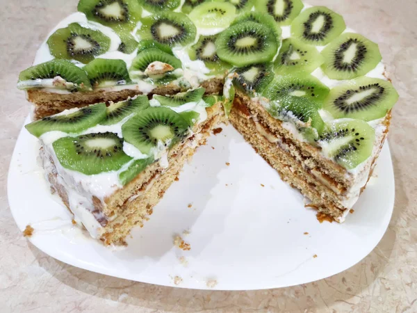 cut cake with kiwi and ice cream on a plate close up