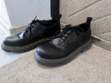 Ön kapıda bir çift siyah kadın ayakkabısı..