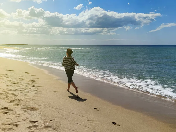 海岸の砂の上を裸足で走る少女トーン写真バックビュー — ストック写真