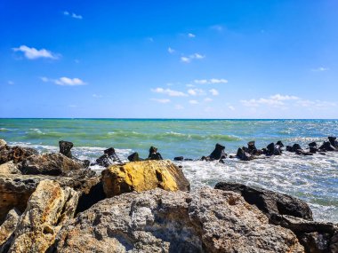 Mavi suyu, kayaları ve mistik yaz gökyüzü olan deniz kıyısı