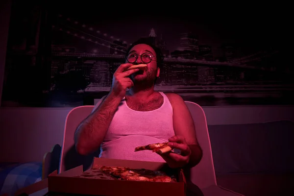 Летний Небритый Толстяк Смотрит Телевизор Показывает Различные Эмоции Ест Пиццу — стоковое фото
