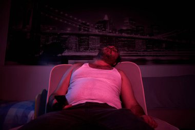 40 yaşında, tıraşsız, kilolu bir adam TV izler, çeşitli duygular gösterir, uyur. Tembel orta yaşlı adam.