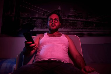 40 yaşında, şişman, tıraş olmamış, gözlüklü bir adam. Elinde uzaktan kumandayla televizyon izleyip çeşitli duygular gösteriyordu. Tembel orta yaşlı adam