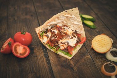 Orta Asya yassı bir ekmeğin içinde ahşap bir arka planda donör ya da shawarma.