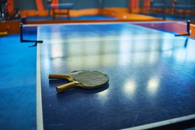 Spor salonunda masa tenisi raketleri olan bir masa. seçici odaklanma, düşük odaklanma derinliği. Sanatsal etki için küçük bir tahıl.