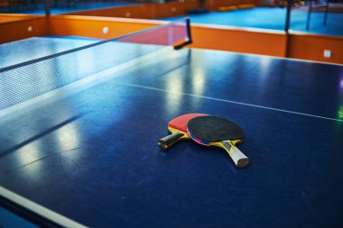 Spor salonunda masa tenisi raketleri olan bir masa. seçici odaklanma, düşük odaklanma derinliği. Sanatsal etki için küçük bir tahıl.