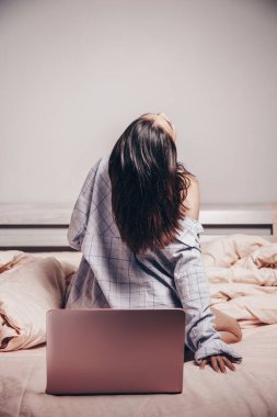 Genç Asyalı bir web kamerası mankeni dizüstü bilgisayarı ile oturuyor. Cazibesini gösteriyor. düşük odak derinliği, seçici odak