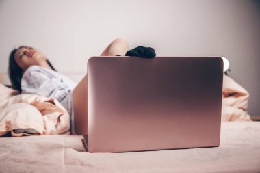 Bilgisayara odaklan. Dizüstü bilgisayarda, genç Asyalı bir kız eğleniyor ve cazibesini gösteriyor. düşük odak derinliği, seçici odak.