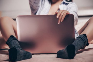 focus on the laptop. at the laptop, a young Asian girl enjoys and shows her charms. low depth of focus,selective focus.
