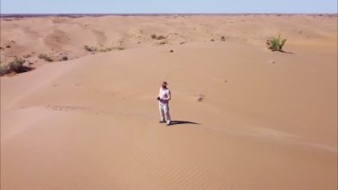 Kumda oturan bir adamın en iyi görüntüsü. Yalnız gezginler çölde yolculuk eder. Çöl bölgesindeki kumulların güzelliğinin tadını çıkarıyorum.