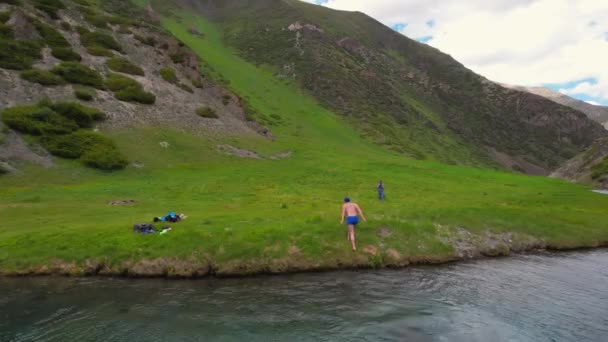 An athlete gets out of a pond in the mountains, shakes his hands — Vídeo de Stock