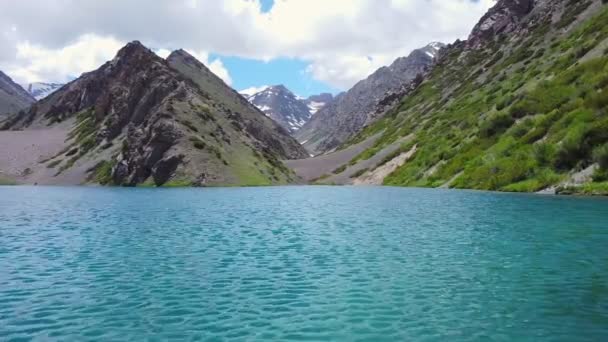 Un dron vuela sobre un lago de montaña turquesa — Vídeos de Stock