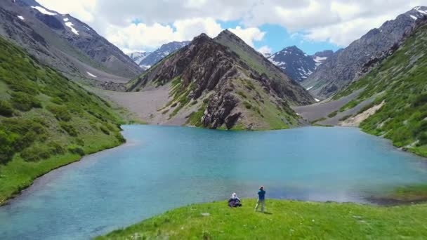 A drone flies over a turquoise mountain lake — Stockvideo